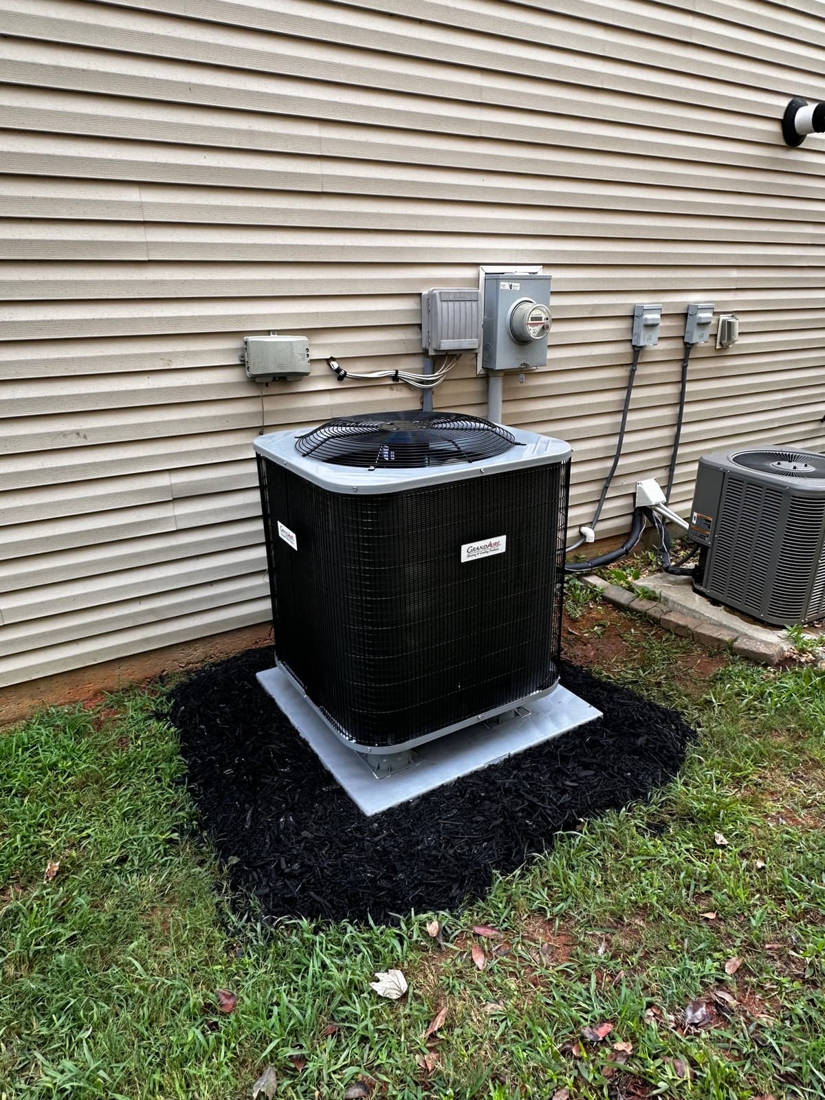 GrandAire outdoor condenser installed beside an existing residential unit