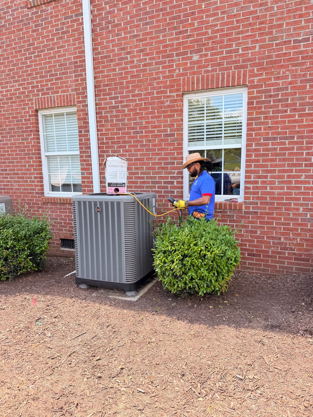 Restore technician checking a residential Ruud outdoor unit with service instruments