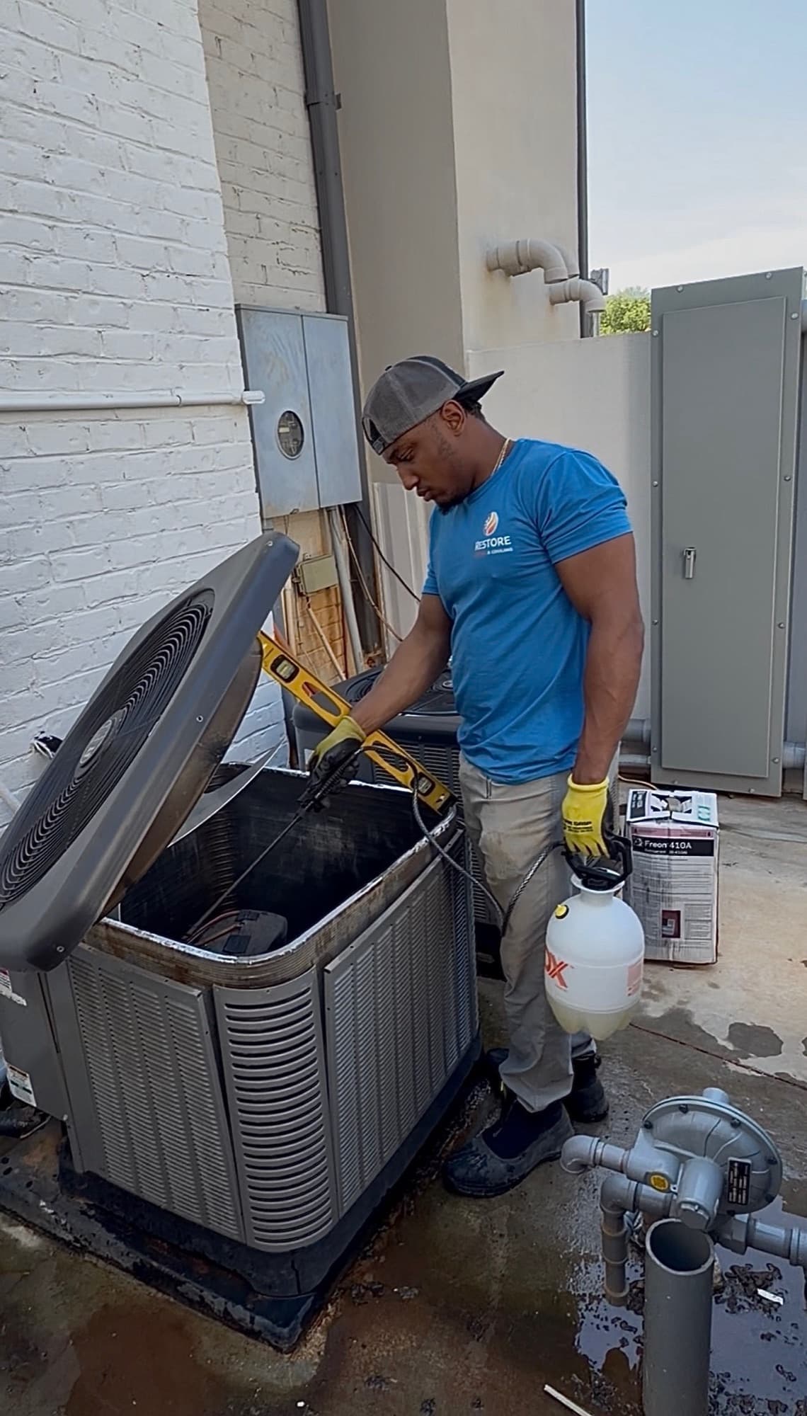 Restore technician cleaning an open residential condenser coil