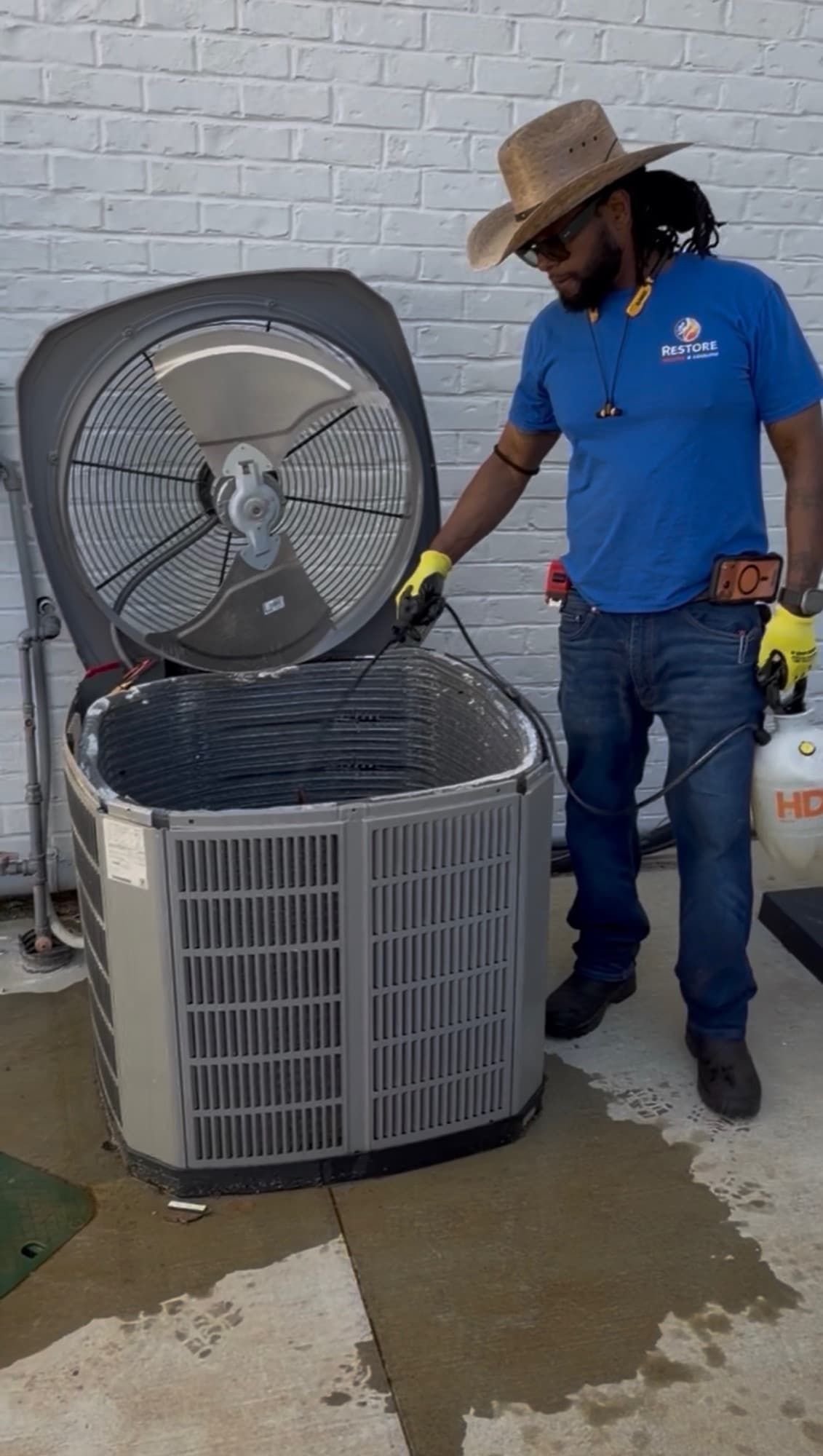 Restore technician rinsing an exposed residential condenser coil