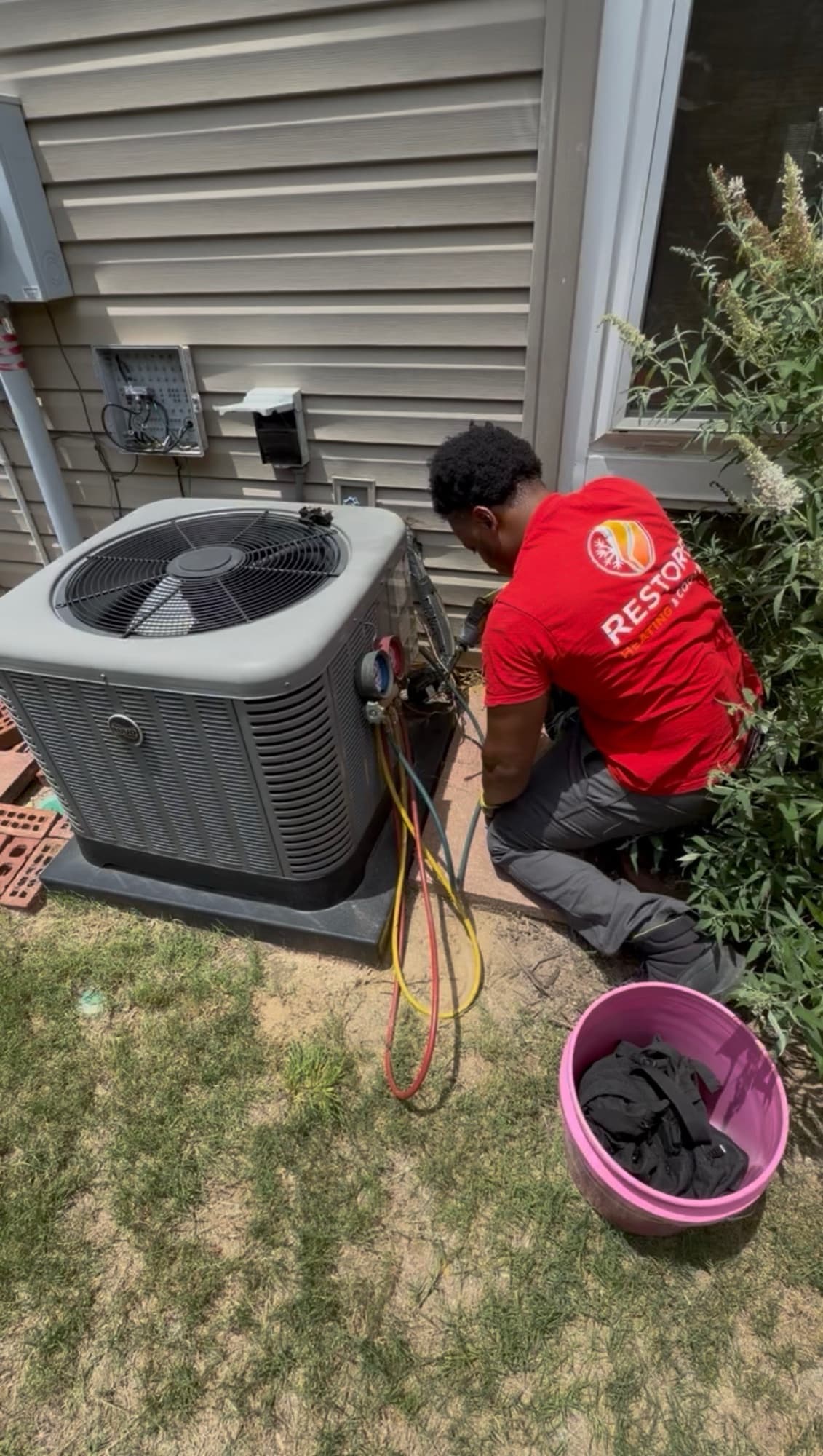 Restore technician using manifold gauges on residential outdoor equipment